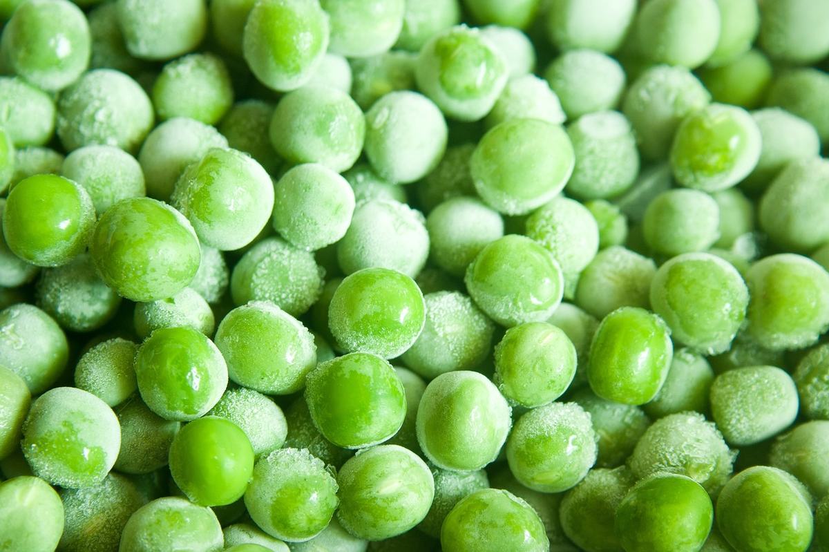 Tiefgefrorene grüne Erbsen mit Eiskristallen in Nahaufnahme
