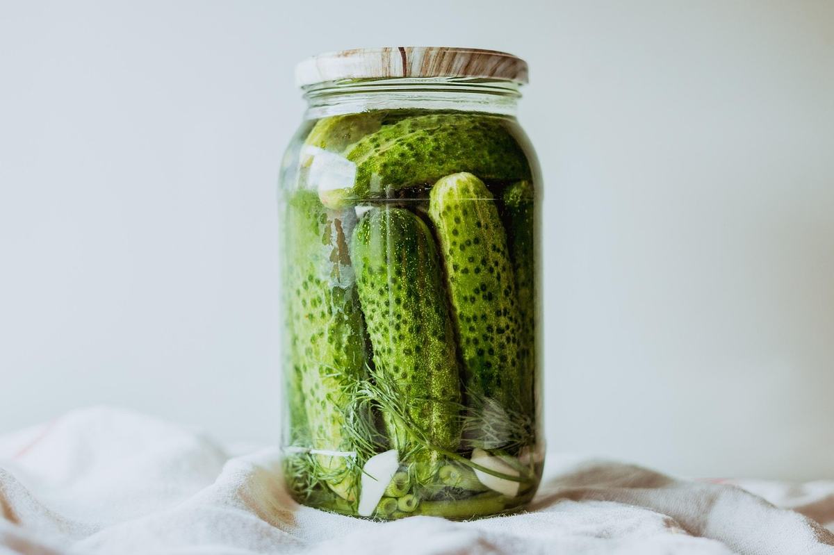 Einmachglas mit ganzen Gurken, Dill und Knoblauch in Lake