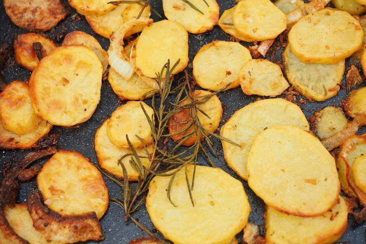 Goldbraun gebratene Kartoffelscheiben mit Rosmarin in einer Pfanne
