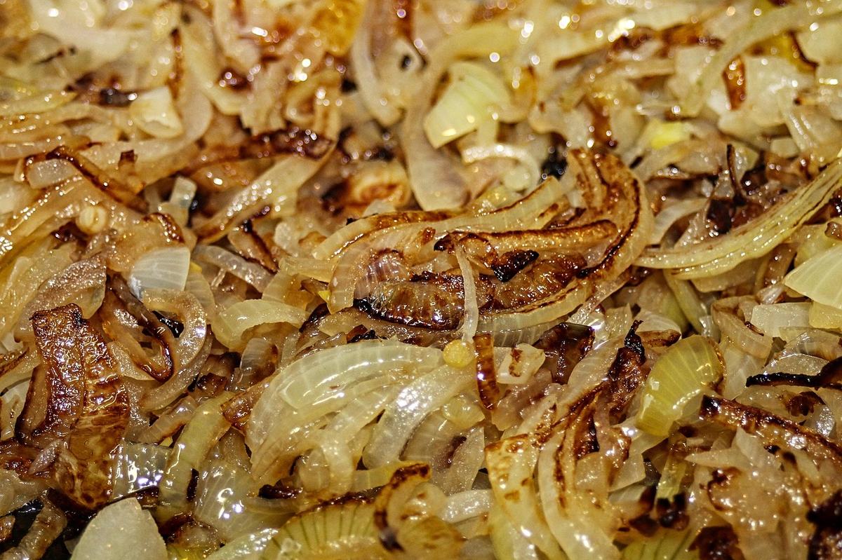 Zwiebelstreifen, die in der Pfanne an den Rändern goldbraun angebraten sind