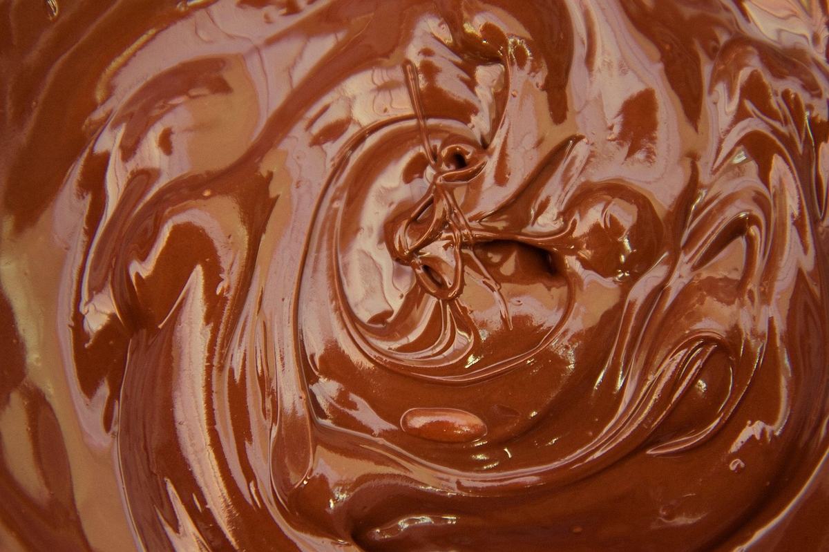 Glänzende, frisch geschmolzene Milchschokolade in Schlieren, von oben fotografiert