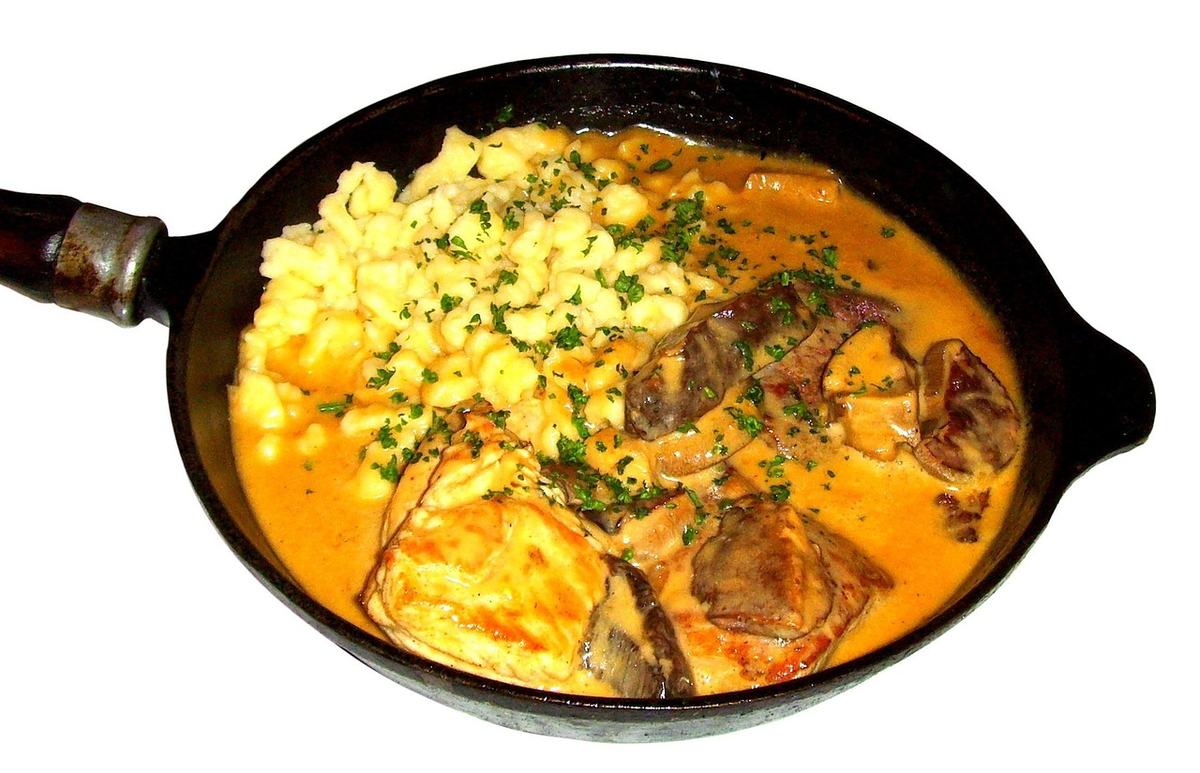 Schweinemedaillons mit Pilzen in heller Rahmsoße und Spätzle in einer gusseisernen Pfanne