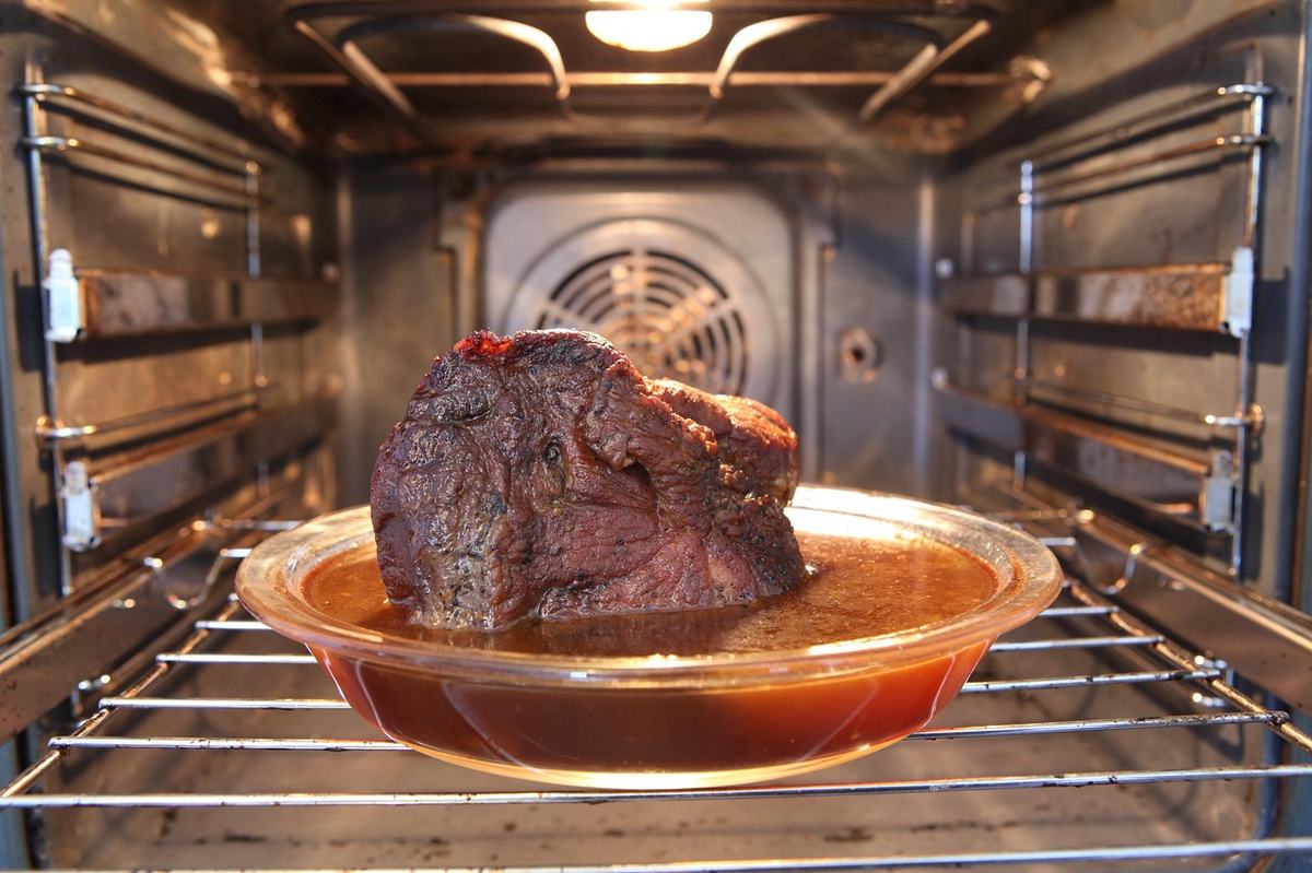 Braten in einer Glasform auf dem Rost im Backofen, hinten der Ventilator in der Rückwand, oben der Grillheizstab