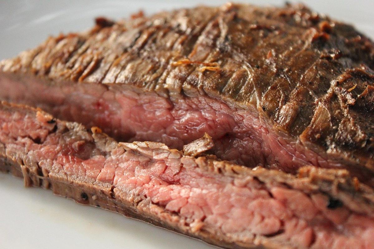 Gegrilltes Flank Steak, angeschnitten, innen rosa, mit gut sichtbaren langen Fleischfasern